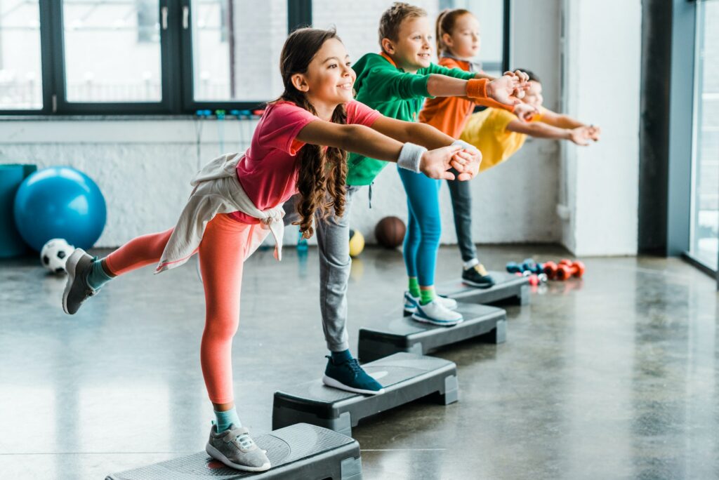 Cheerful kids doing exercises with step platforms